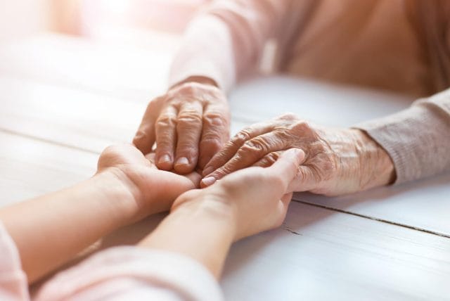 A close-up of a young person's hands holding an older person's hands.