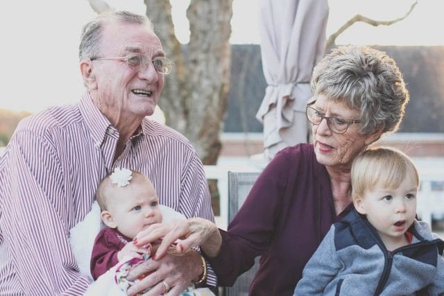 An older adult couple sit with their grandchildren.