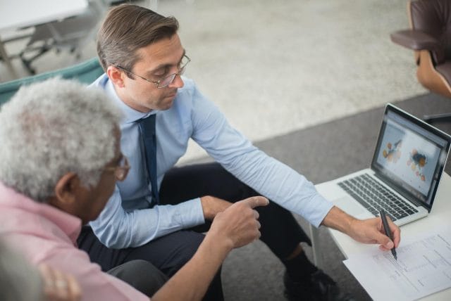 A business man explains information in a contract to an older adult.